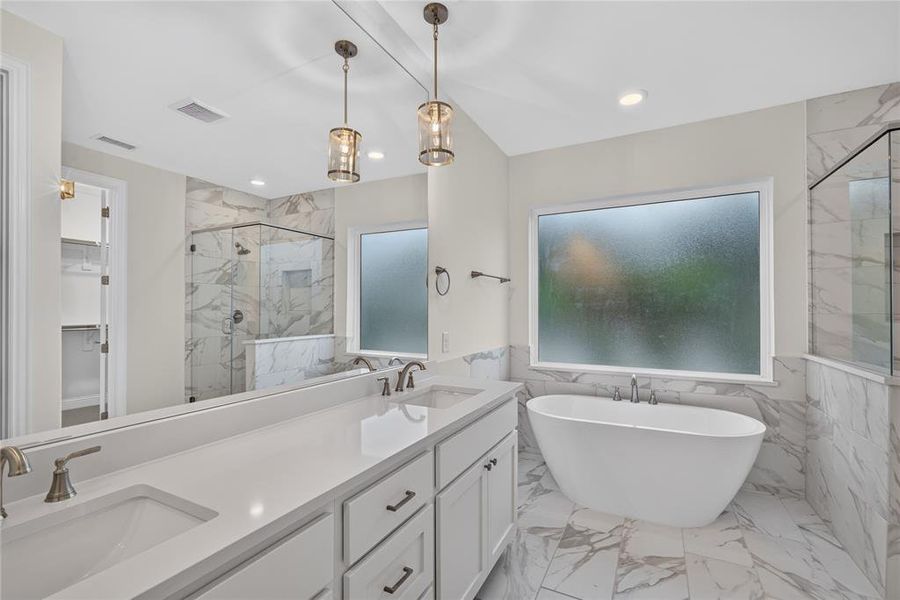 Contemporary bathroom featuring a freestanding tub, a spacious glass-enclosed shower, a double vanity with an integrated countertop, and large-format tile flooring Contemporary bathroom featuring a freestanding tub, a spacious glass-enclosed shower, a double vanity with an integrated countertop, and large-format tile flooring