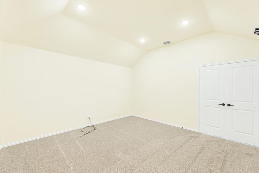 Empty bedroom with vaulted ceiling, carpet flooring, recessed lights, and white double doors Empty bedroom with vaulted ceiling, carpet flooring, recessed lights, and white double doors