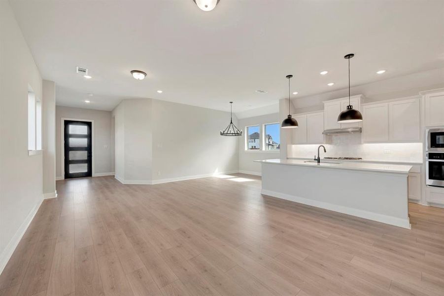 Kitchen with white cabinets, open floor plan, a kitchen island with sink, and stainless steel appliances