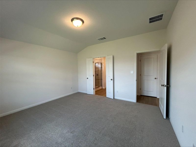 Unfurnished bedroom with vaulted ceiling, carpet flooring, and ensuite bathroom
