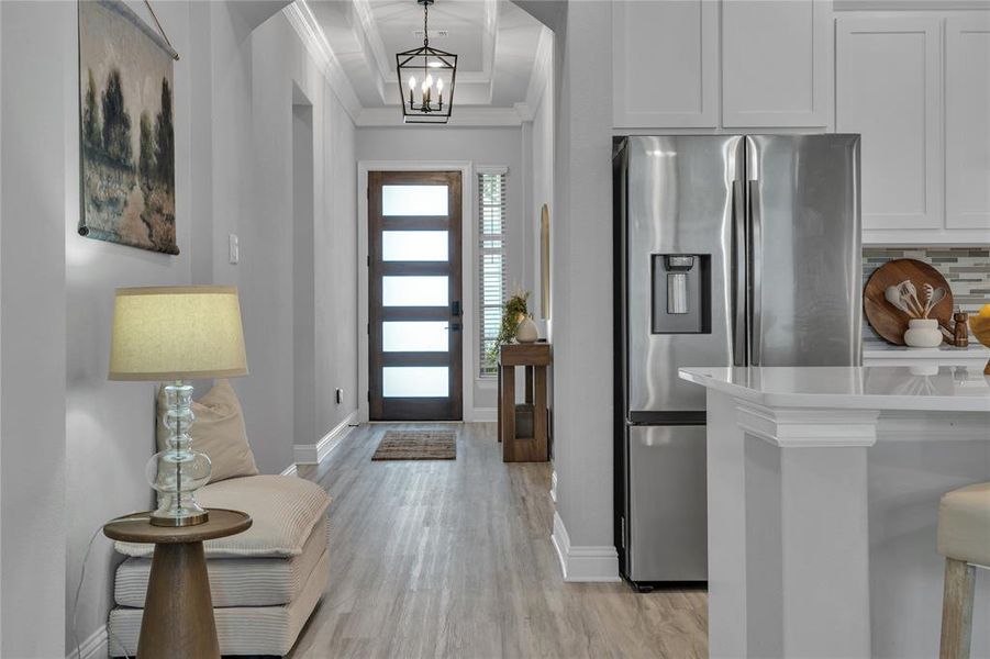 Foyer featuring light wood-style flooring, ornamental molding, and a chandelier Foyer featuring light wood-style flooring, ornamental molding, and a chandelier