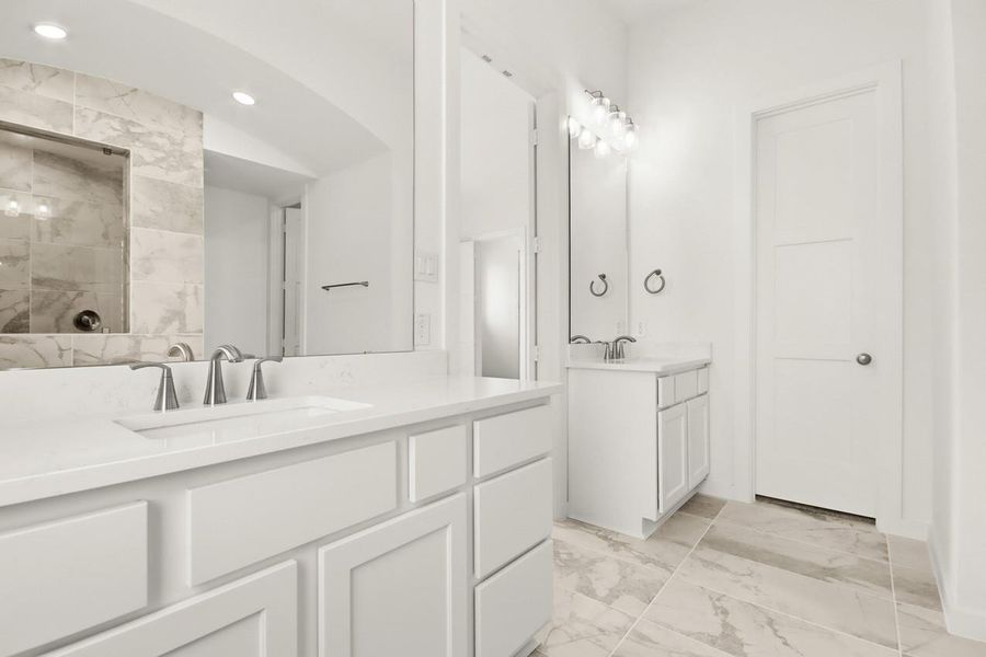 Primary bathroom featuring dual sinks separated by a central door, creating a functional split layout that enhances privacy and convenience.
