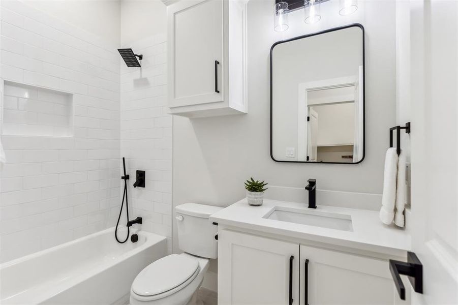 Full bathroom with tiled shower / bath, vanity, and toilet