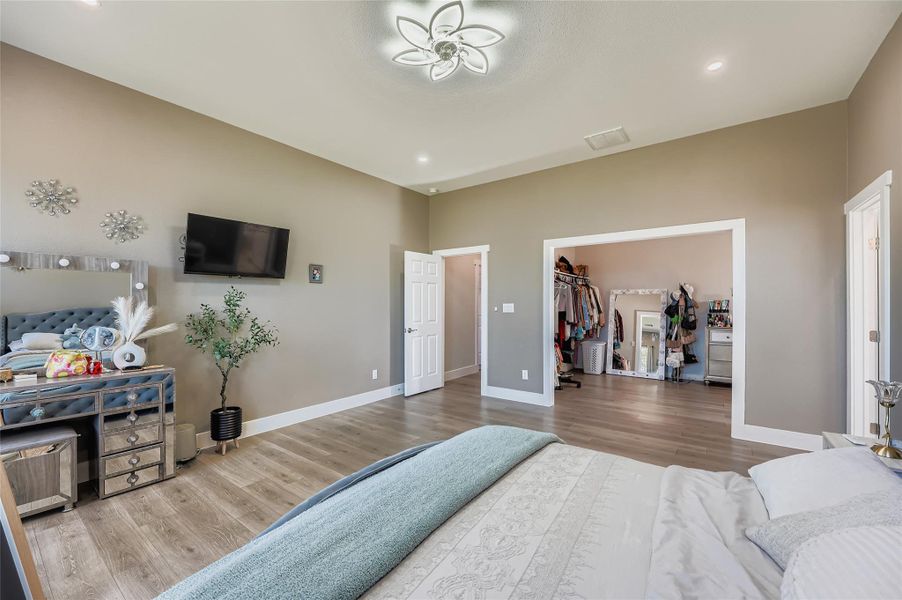 Bedroom featuring a spacious closet, wood finished floors, and recessed lighting Bedroom featuring a spacious closet, wood finished floors, and recessed lighting