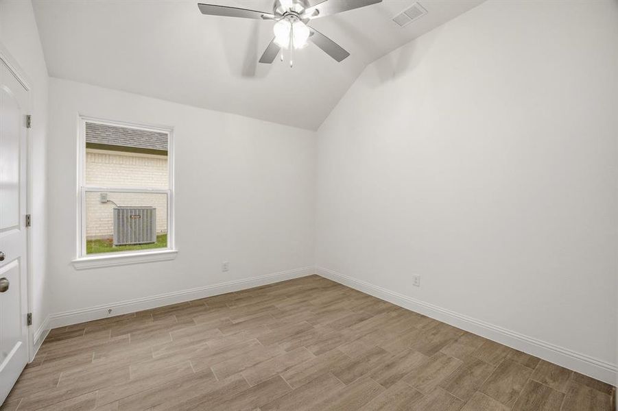 This room features an angled ceiling, a ceiling fan, and tile flooring