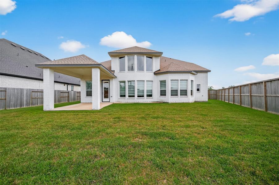 Fully fenced backyard with lush lawn and a rear view showcasing the home’s stunning architecture and outdoor living potential.