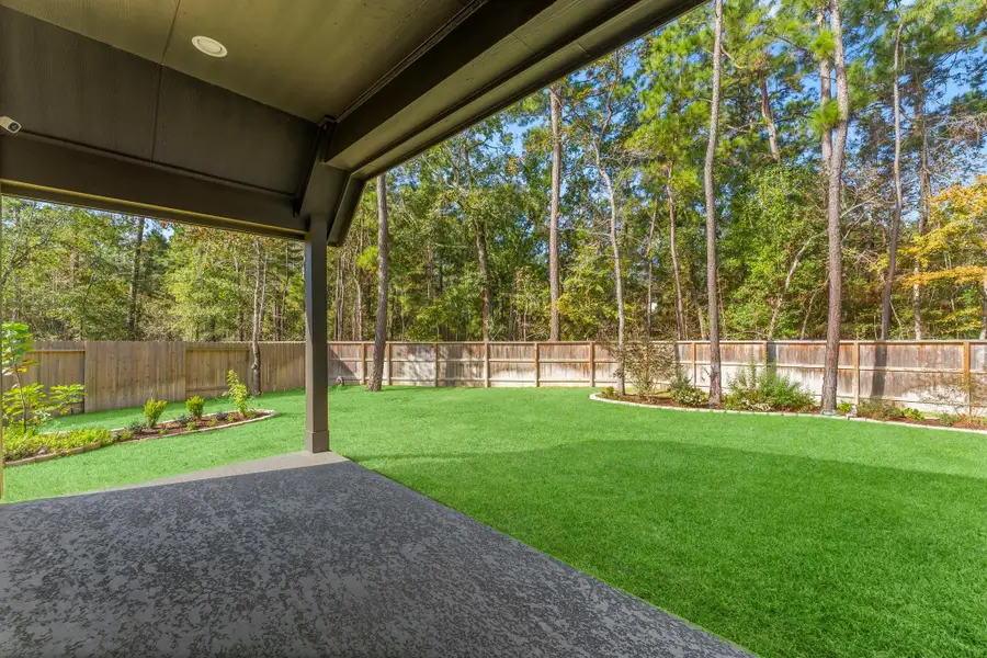 The covered back patio is the perfect place to relax and take in the serene backyard.