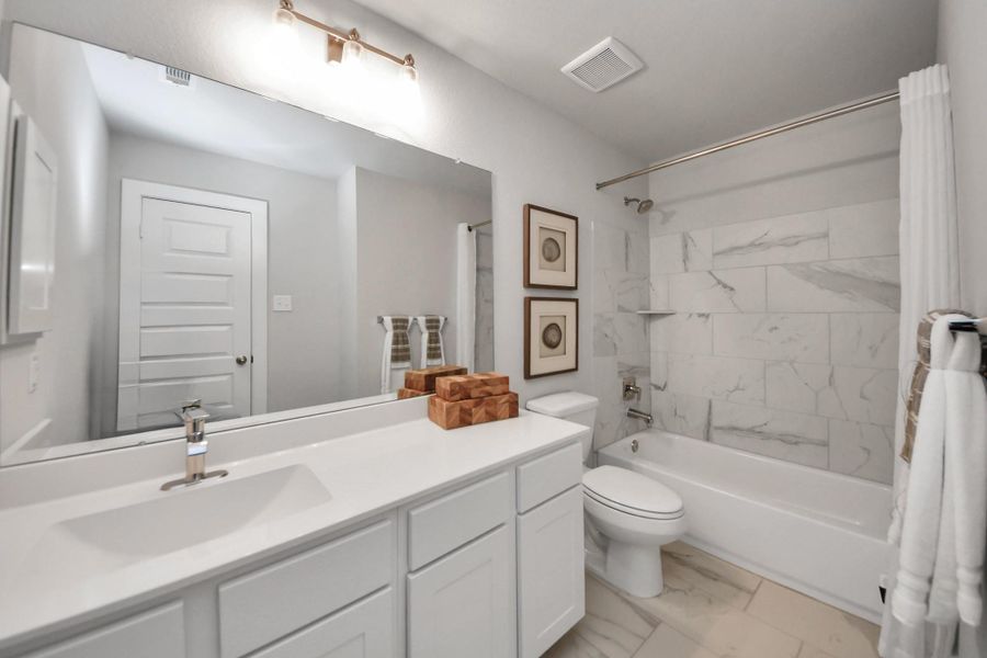 Secondary bath features tile flooring, bath/shower combo with tile surround, light stained wood cabinets, beautiful light countertop. Secondary bath features tile flooring, bath/shower combo with tile surround, light stained wood cabinets, beautiful light countertop.