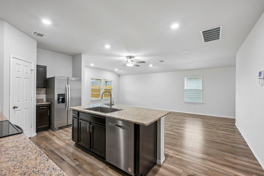 Open-concept kitchen and living area featuring wood-finish flooring, recessed lighting, and a ceiling fan