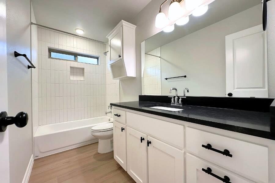 Bathroom featuring bathtub / shower combination, vanity, and light wood-style flooring