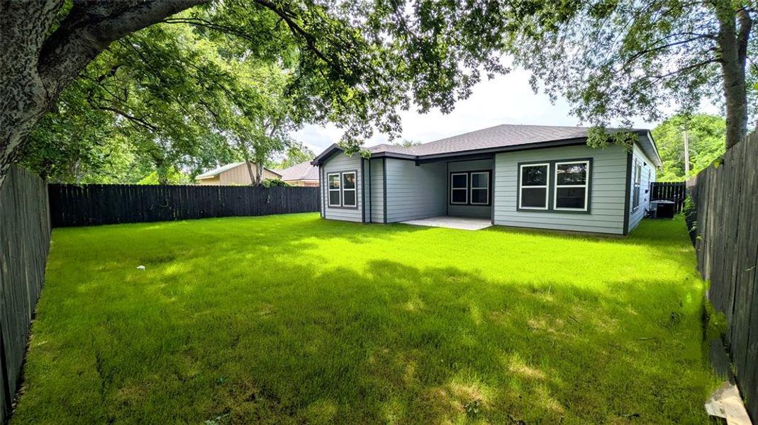 Back of property with a fenced backyard, a lawn, and a patio area