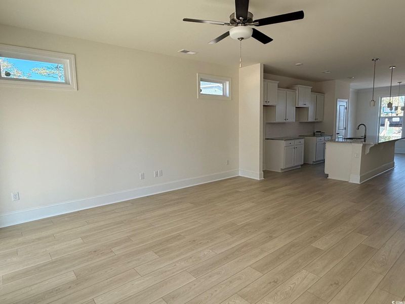 Unfurnished living room featuring light wood-type flooring and a ceiling fan