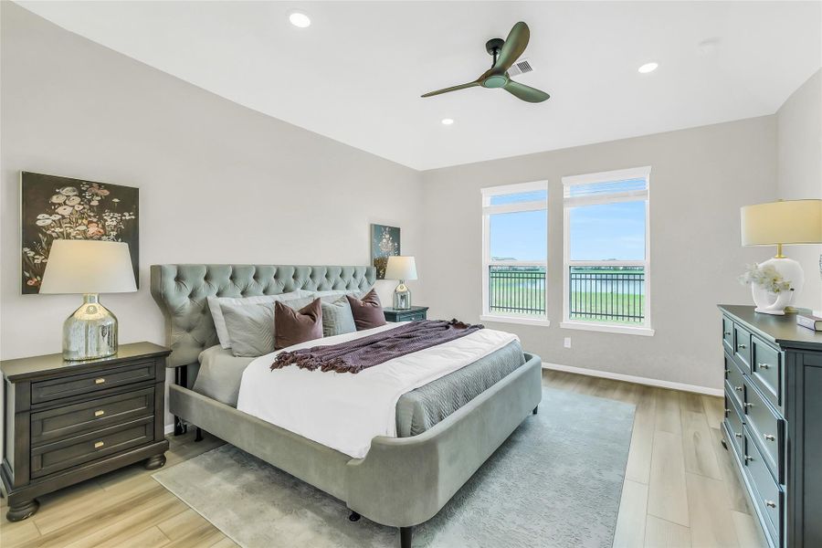 This expansive primary suite is a true retreat, featuring recessed lighting, a modern ceiling fan, and large windows that invite an abundance of natural light and beautiful lake view