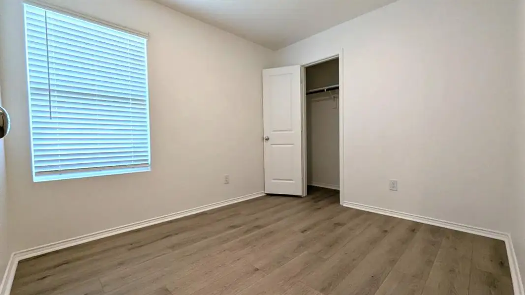 Unfurnished bedroom featuring wood finished floors and a walk-in closet Unfurnished bedroom featuring wood finished floors and a walk-in closet