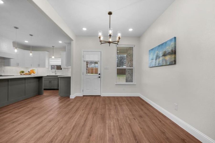 Unfurnished dining area with sink, a chandelier, and light wood-type flooring