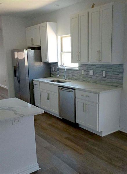 Kitchen with white cabinets, dark wood-type flooring, appliances with stainless steel finishes, and sink