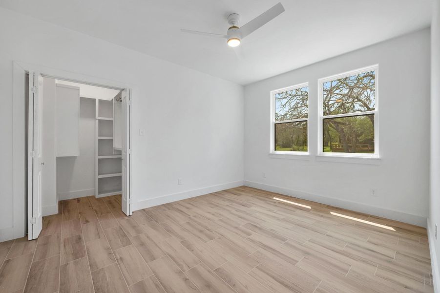 Unfurnished bedroom with a spacious closet, light wood-style flooring, and ceiling fan Unfurnished bedroom with a spacious closet, light wood-style flooring, and ceiling fan