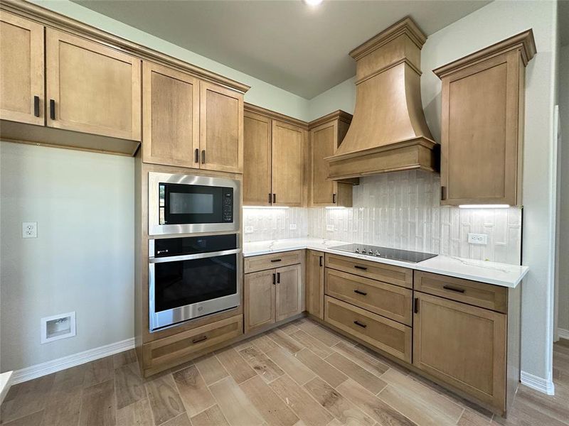 Kitchen with stainless steel oven, built in microwave, tasteful backsplash, wood finish floors, and black electric cooktop