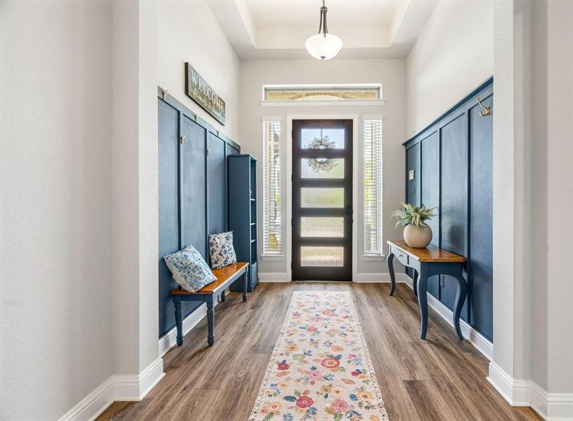 Entryway featuring wood-finish flooring, a contemporary pendant light, and a high ceiling with tray detailing Entryway featuring wood-finish flooring, a contemporary pendant light, and a high ceiling with tray detailing