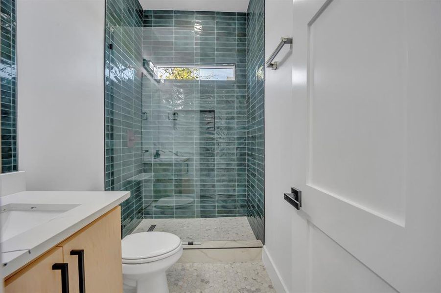 Bathroom featuring vanity, toilet, and a tile shower