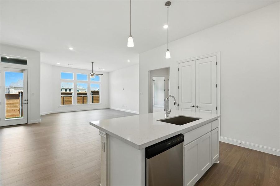 Kitchen featuring white cabinets, dishwasher, dark wood-style floors, decorative light fixtures, and light stone countertops