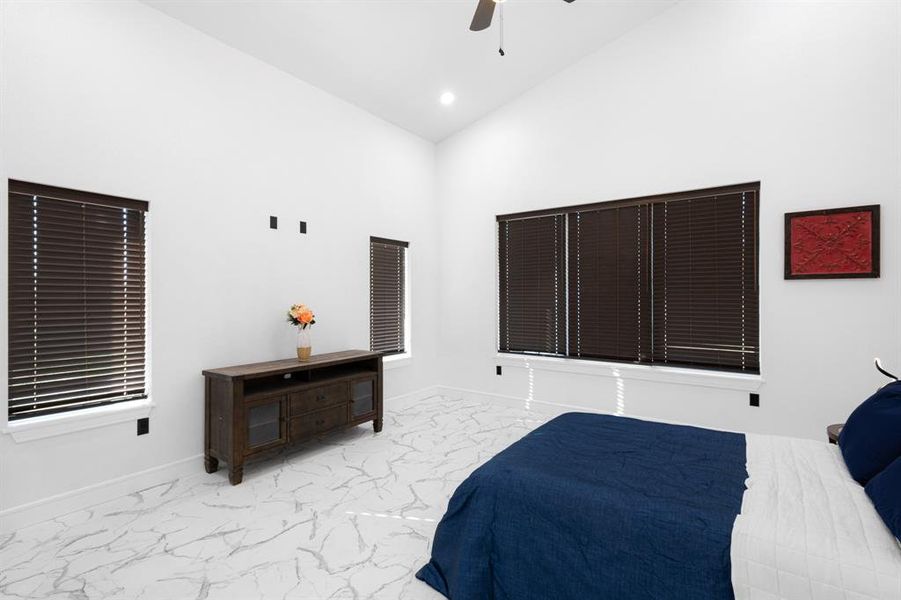 Bedroom featuring marble finish flooring, ceiling fan, recessed lighting, and a towering ceiling