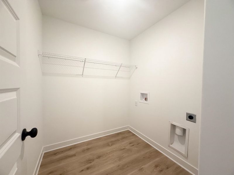 Washroom with hookup for an electric dryer, washer hookup, and light wood-style floors