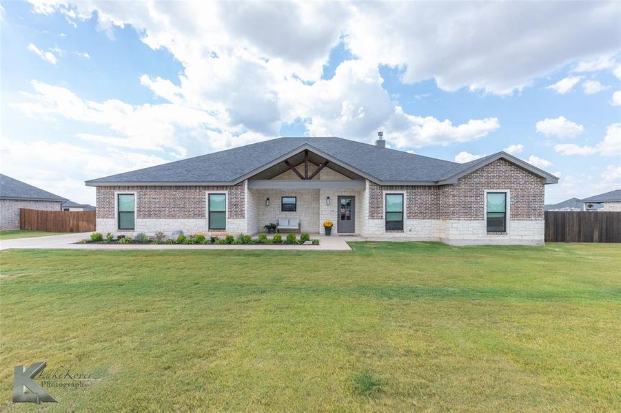 View of front facade with brick siding, a porch, a shingled roof, and stone siding View of front facade with brick siding, a porch, a shingled roof, and stone siding