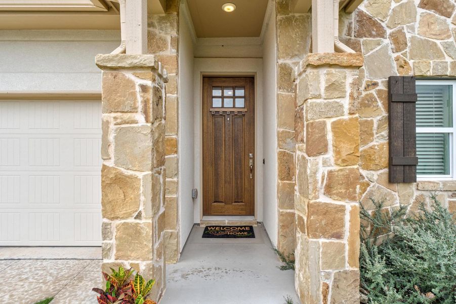 Entrance to property featuring a garage and stone siding
