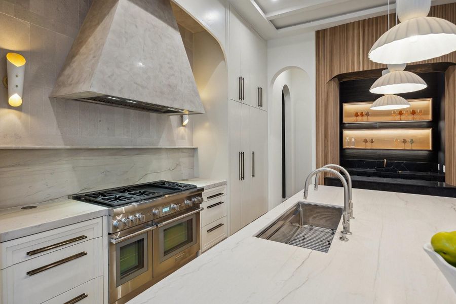 A closer look at the back of the Kitchen offers a custom hood with a Thermador Liner, finished in Concretta Plaster, Honed Quartzite Counter and Backsplash, Sconce lighting, Flush Mount, Dual Sided Pop-Up Counter Power Outlets. Single Basin Undermount Hamat Stainless Steel Sink with Two Rohl Pull-Out Spray Kitchen Faucets. A closer look at the back of the Kitchen offers a custom hood with a Thermador Liner, finished in Concretta Plaster, Honed Quartzite Counter and Backsplash, Sconce lighting, Flush Mount, Dual Sided Pop-Up Counter Power Outlets. Single Basin Undermount Hamat Stainless Steel Sink with Two Rohl Pull-Out Spray Kitchen Faucets.