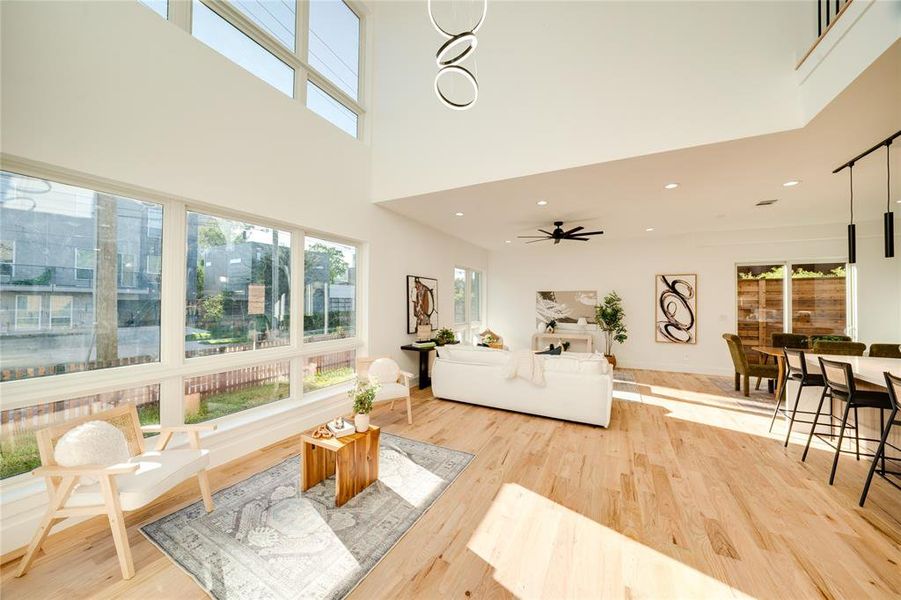 Living room featuring wood-type flooring, a high ceiling, and ceiling fan