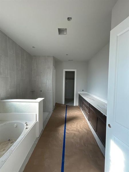 Full bathroom with a bath, vanity, a walk in closet, walk in shower, and concrete flooring