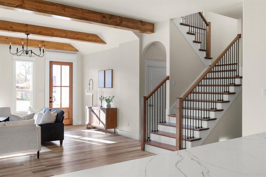 Entryway featuring beamed ceiling, light hardwood / wood-style flooring, and a notable chandelier