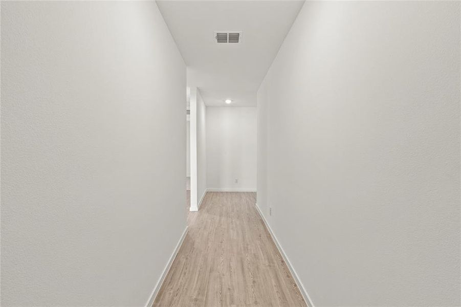 Hallway featuring wood-finish flooring, recessed lighting, and crisp white walls