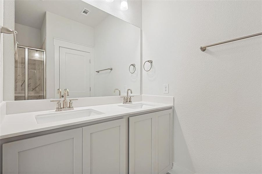 The bathroom features a double vanity with light-colored cabinetry and countertops, brushed nickel faucets, and a large wall-mounted mirror