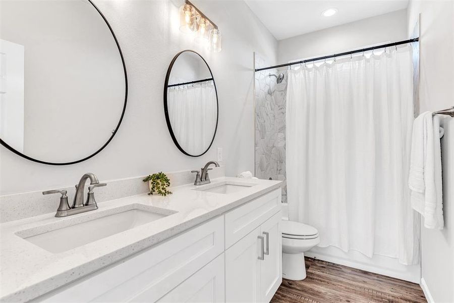 Upstairs Bathroom with double vanity, wood-type flooring, and toilet