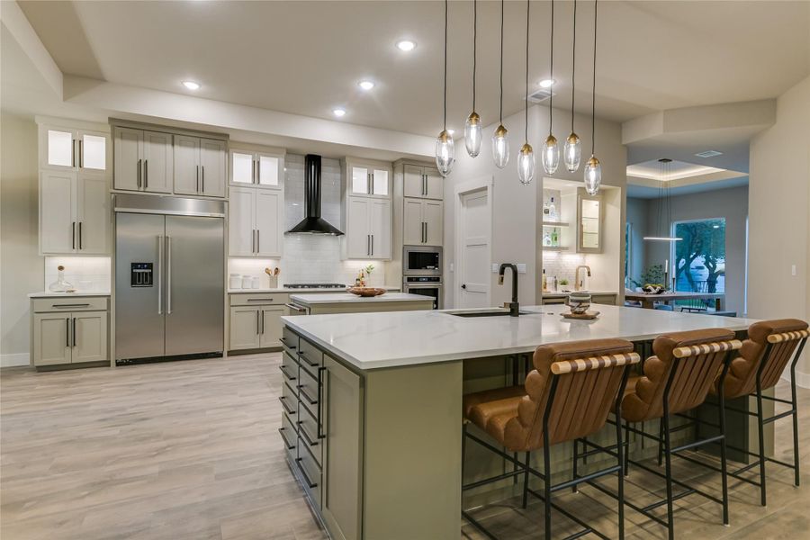 Kitchen with backsplash, glass insert cabinets, built in appliances, a kitchen breakfast bar, and hanging light fixtures Kitchen with backsplash, glass insert cabinets, built in appliances, a kitchen breakfast bar, and hanging light fixtures