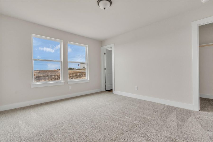 Sun-filled windows illuminate this carpeted room, offering expansive views of the surrounding landscape.
