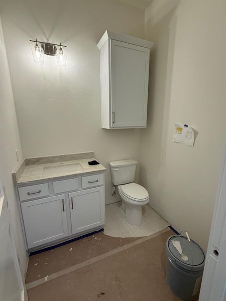 Bathroom featuring a white vanity with an integrated sink, a light-toned countertop, and a wall-mounted light fixture with clear glass shades