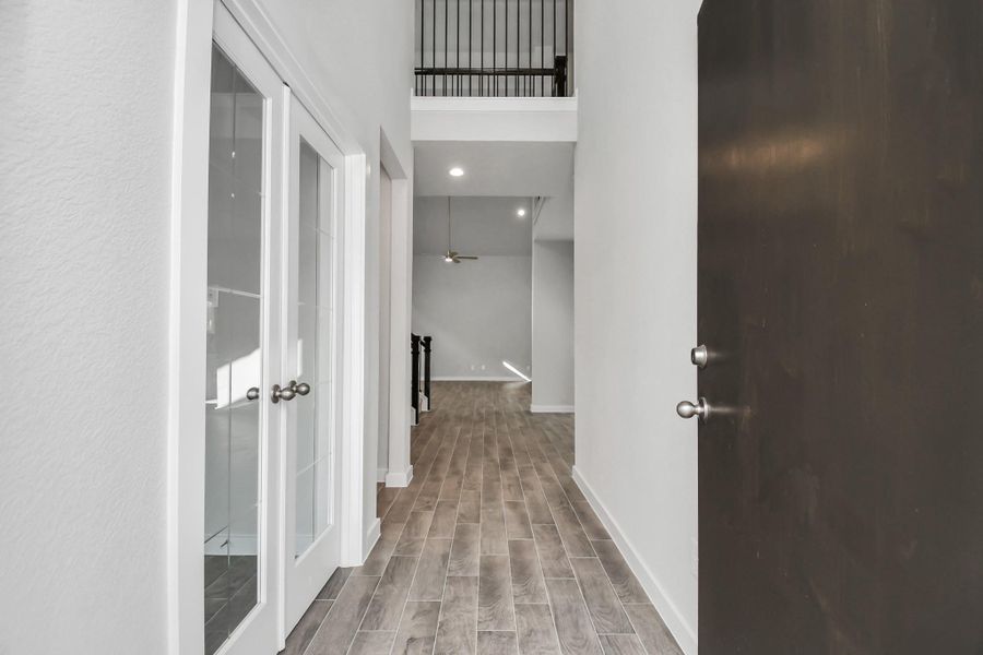 The majestic entryway allures with its high ceilings, embellished with sophisticated wood-look tile flooring and sleek oversized baseboards. Lift your eyes to a captivating sight of the open staircase, and follow the trail of natural light pouring in through expansive windows as you journey to the family room, crafting an inviting and cozy ambiance. Sample photo of completed home with similar floor plan. Actual colors and selections may vary. The majestic entryway allures with its high ceilings, embellished with sophisticated wood-look tile flooring and sleek oversized baseboards. Lift your eyes to a captivating sight of the open staircase, and follow the trail of natural light pouring in through expansive windows as you journey to the family room, crafting an inviting and cozy ambiance. Sample photo of completed home with similar floor plan. Actual colors and selections may vary.