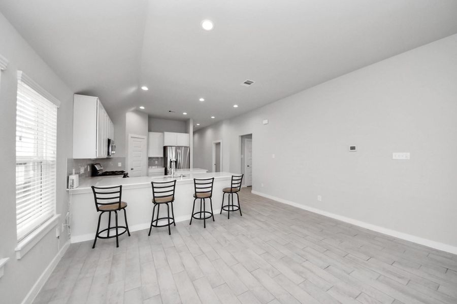 Spacious dining area located just off the kitchen, featuring a large breakfast bar with seating and an open layout that allows for flexible dining and entertaining.