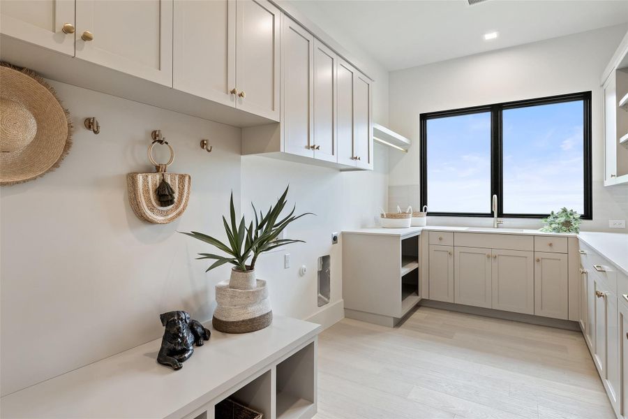 Laundry area with a sink, light wood-style floors, and cabinet space Laundry area with a sink, light wood-style floors, and cabinet space
