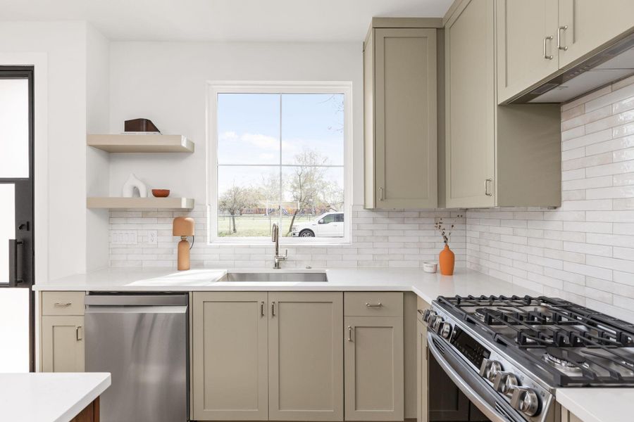 Kitchen with stainless steel appliances, open shelves, light stone countertops, and tasteful backsplash
