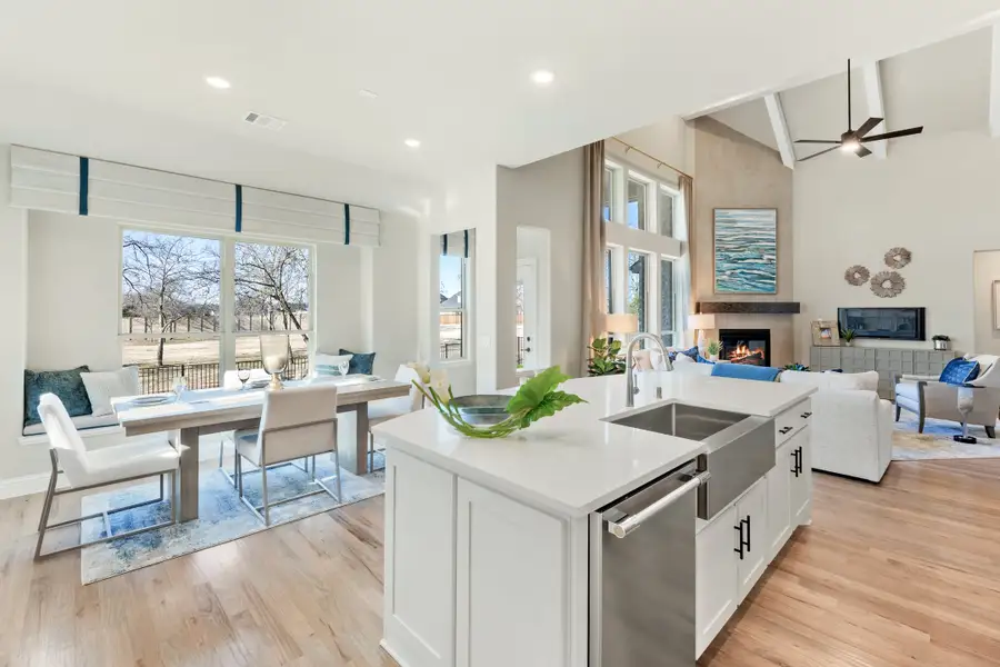Open-concept kitchen with white island flowing into dining area and living room with vaulted ceiling and fireplace Open-concept kitchen with white island flowing into dining area and living room with vaulted ceiling and fireplace