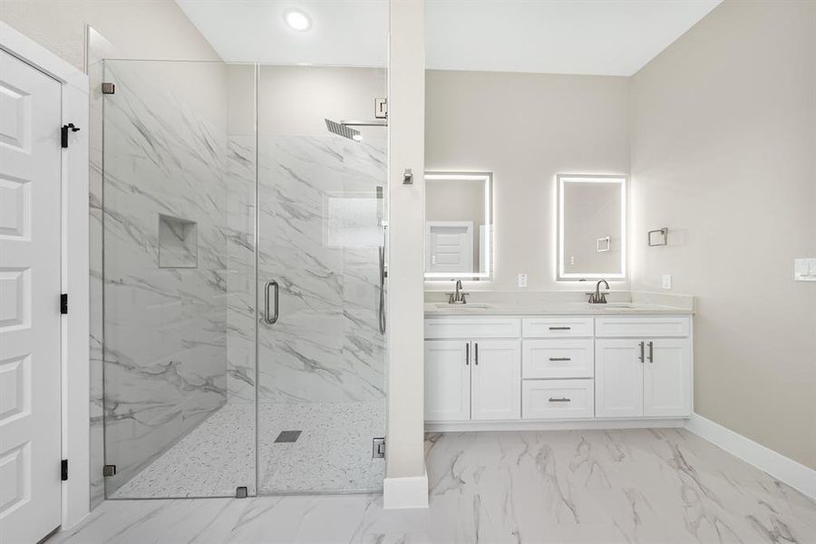 Primary bedroom bathroom featuring a marble finish shower, marble finish flooring, double vanity, and recessed lighting Primary bedroom bathroom featuring a marble finish shower, marble finish flooring, double vanity, and recessed lighting