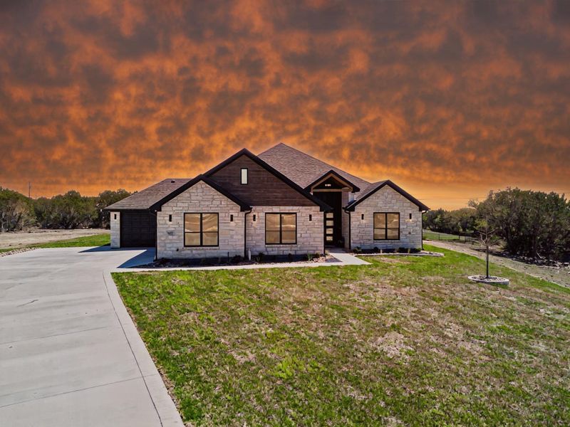 View of front facade with stone siding, driveway, a front yard, and a garage View of front facade with stone siding, driveway, a front yard, and a garage