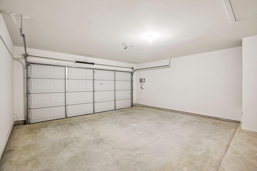 An attached multi-car garage features a durable concrete floor and white walls.
