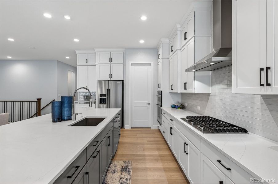 Kitchen (Alternate View) – Sleek and modern kitchen design featuring white shaker cabinetry, stainless steel appliances, and an oversized island with a built-in sink and designer fixtures.