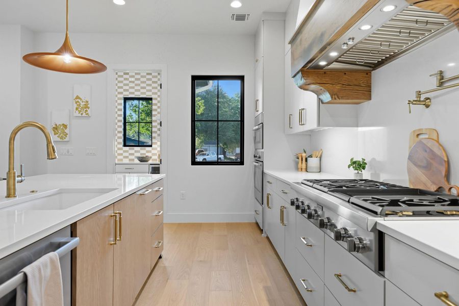 Kitchen with hanging light fixtures, stainless steel appliances, light wood finished floors, white cabinets, and recessed lighting Kitchen with hanging light fixtures, stainless steel appliances, light wood finished floors, white cabinets, and recessed lighting