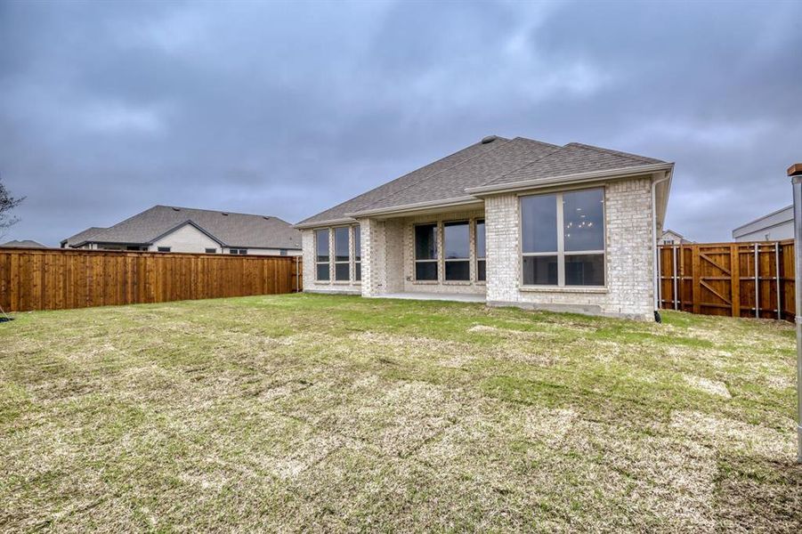 Rear view of property with brick siding, a patio area, a fenced backyard, and a shingled roof
